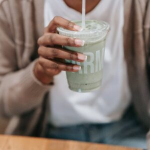 woman drinking juice through a straw and using a tablet